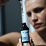 Model holding Algae Bioactive Concentrate Face Oil bottle with dropper above