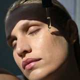 Model applying Algae Bioactive Concentrate Face Oil to cheek using dropper