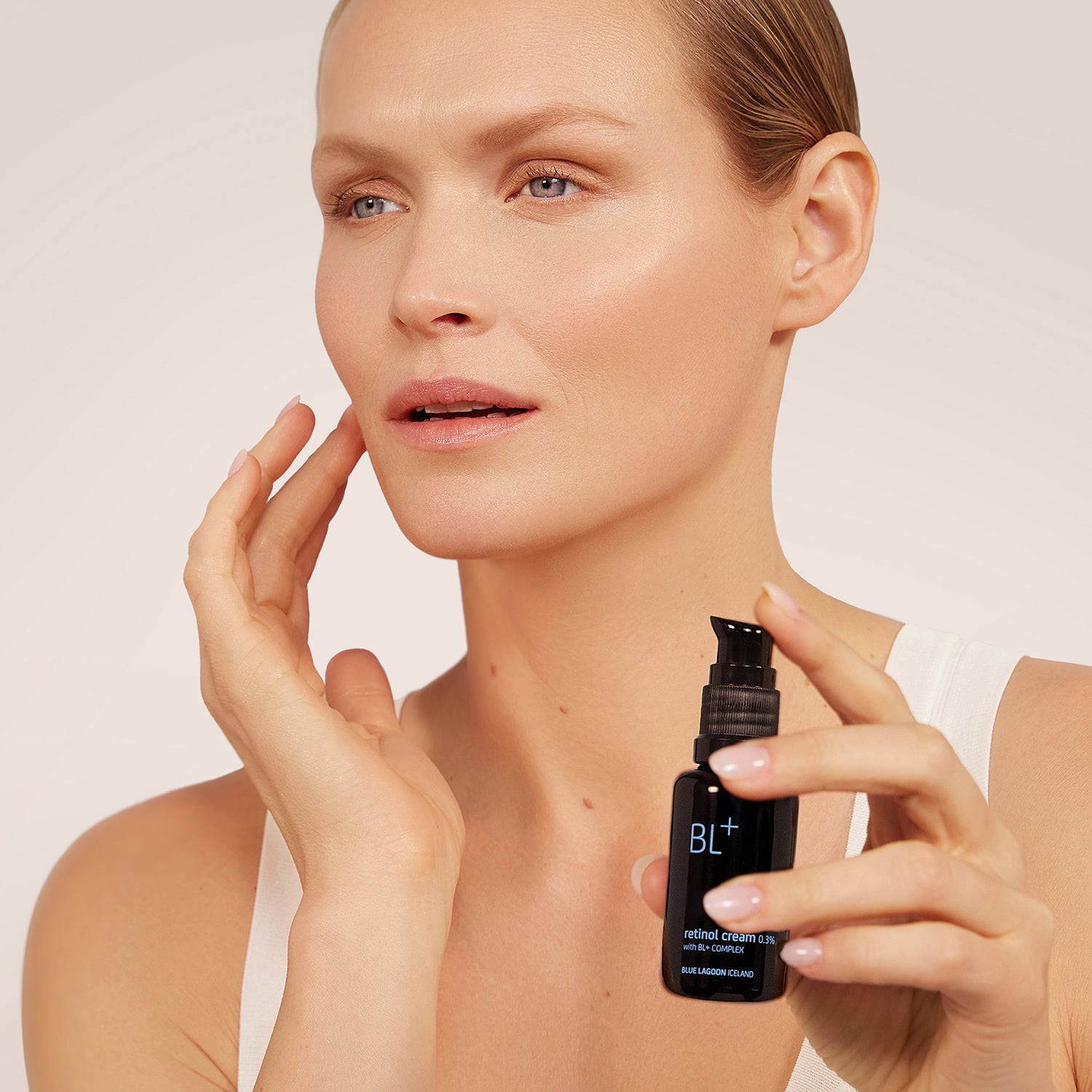 Model holding BL+ Retinol Cream 0.3% while applying product to face