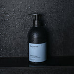 Shower Gel pump bottle standing on wet stone surface in shower setting