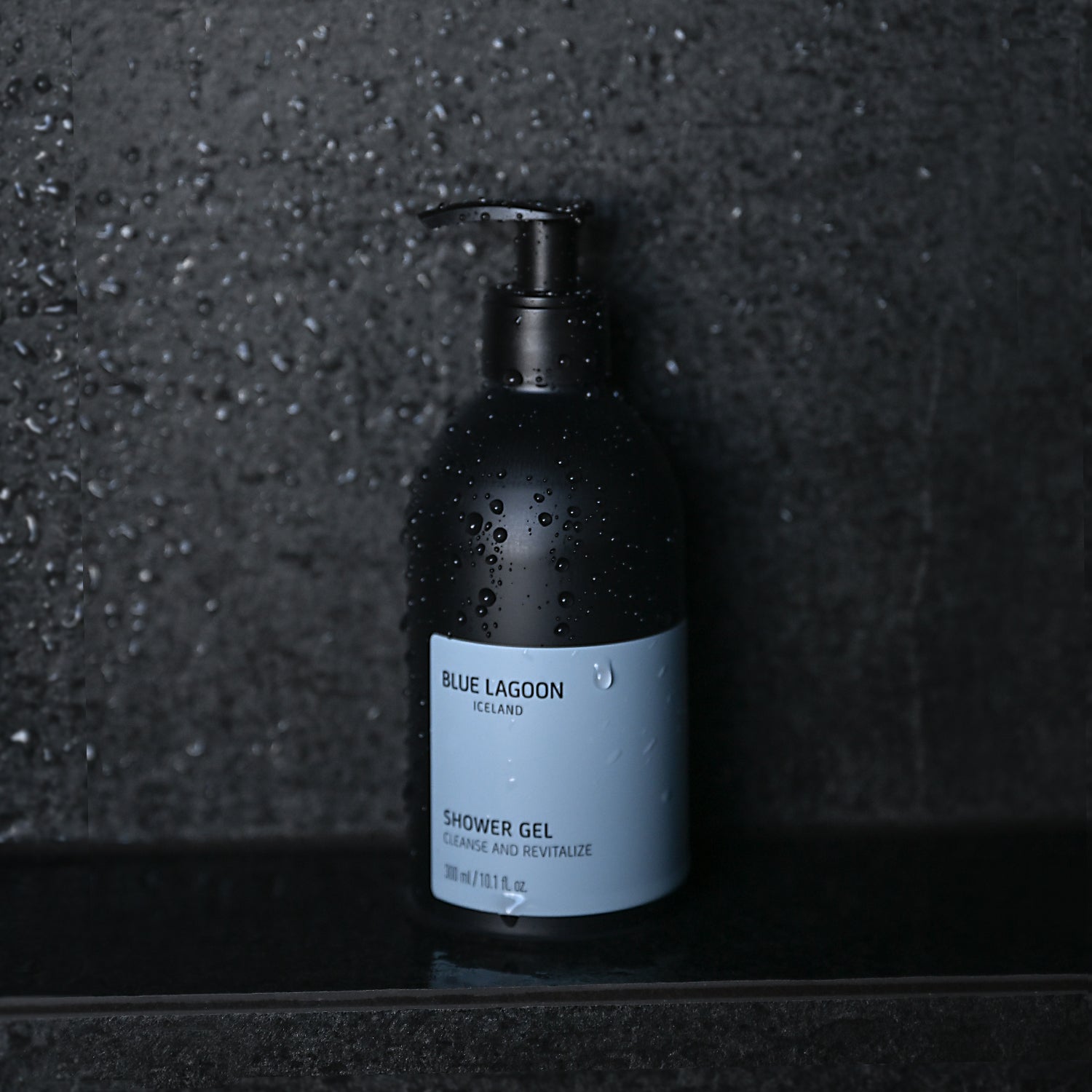 Shower Gel pump bottle standing on wet stone surface in shower setting