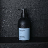 17oz Conditioner bottle standing on wet stone surface in shower setting