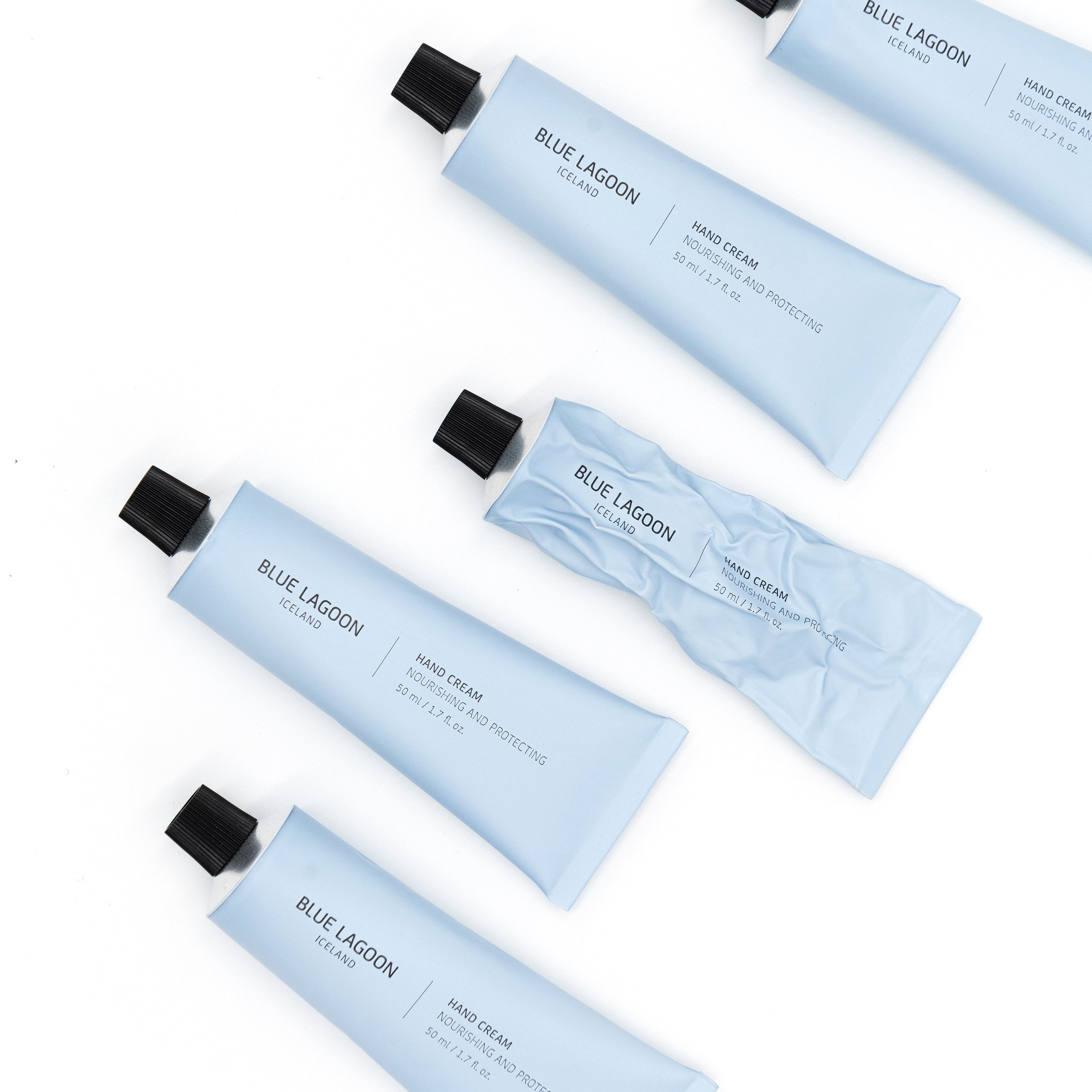 Hand Cream tubes arranged on white background, one tube partially squeezed