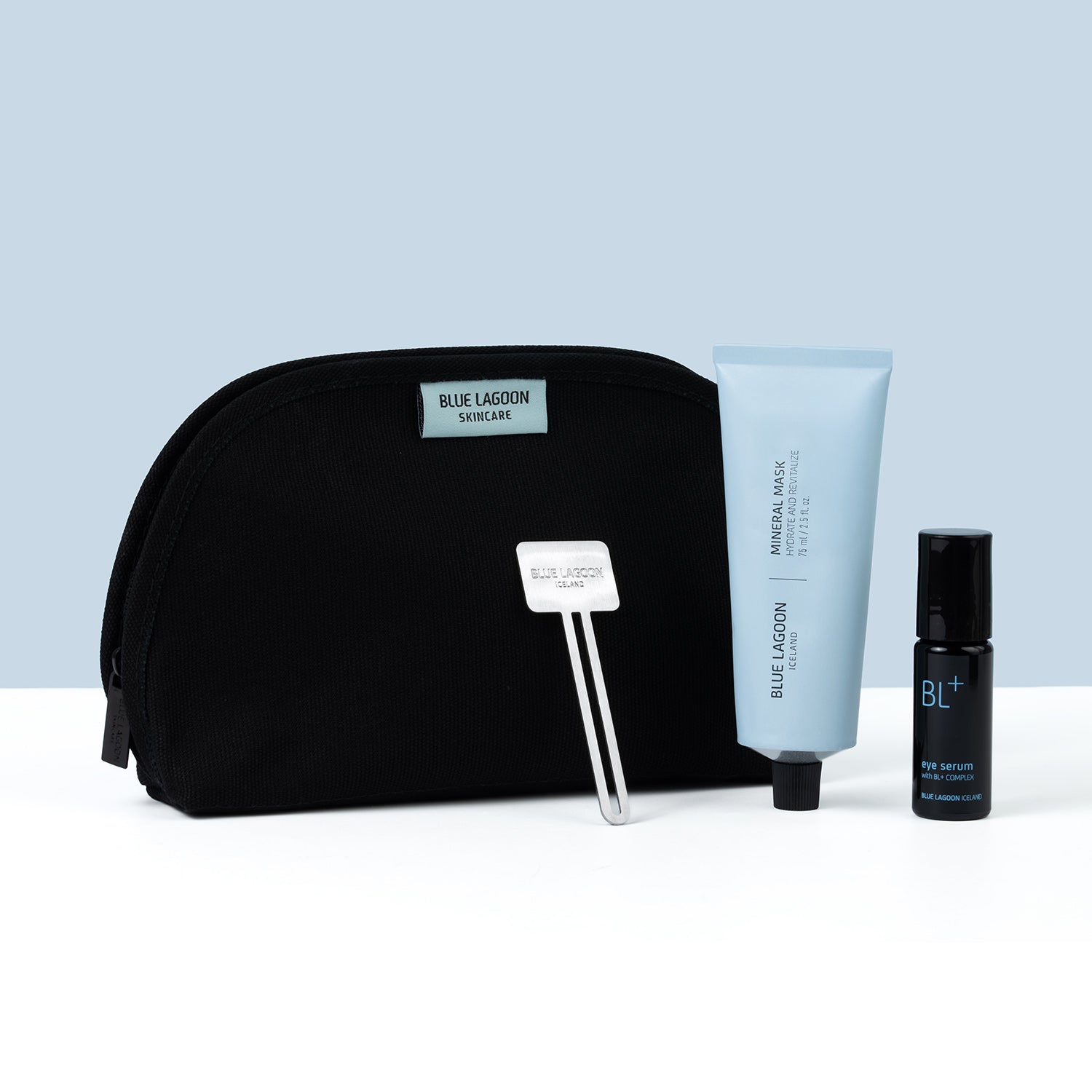Cosmetic bag with eye serum, mineral mask, and tube squeezer on a blue background