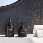 Hand Wash and Hand Lotion bottles on bathroom counter with folded towel