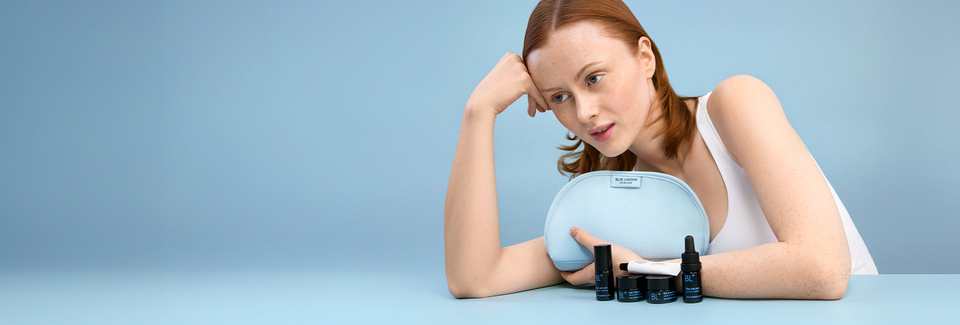 Woman holding a blue round object with cosmetic products on a light blue background